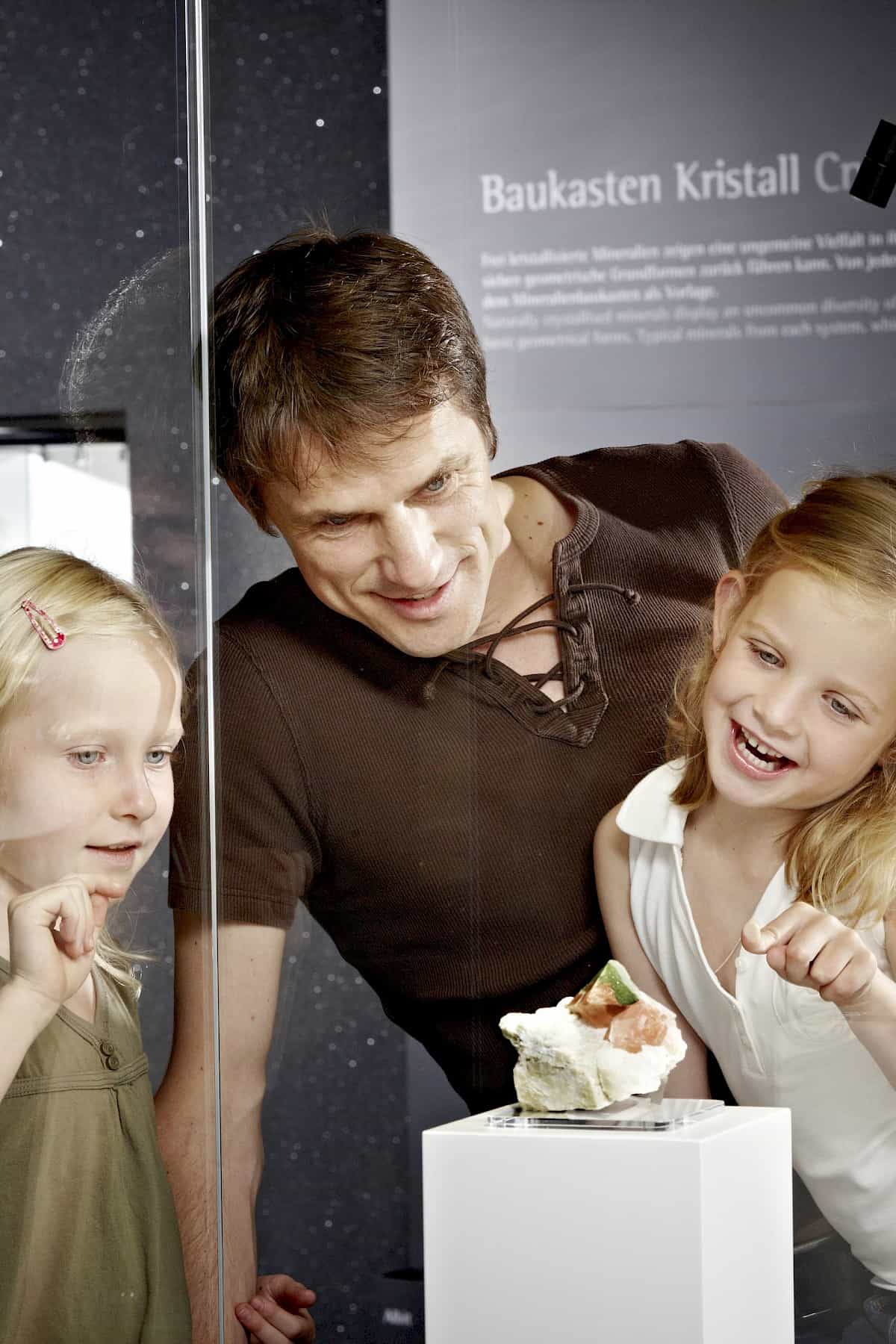 Children and father admire minerals at the Bramberg Museum – crystal and gemstone exhibition in Hohe Tauern National Park, family-friendly attraction in the Wildkogel Arena.
